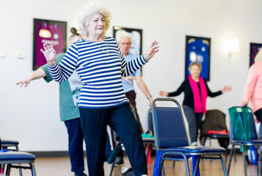 Older Woman Doing A Low Intensity Exercise Class With Other People