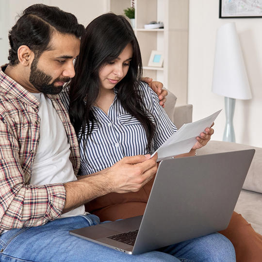 Couple On Laptop Looking At Form