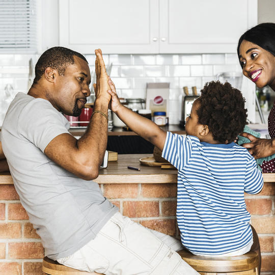 Family High Fiving In Kitchen