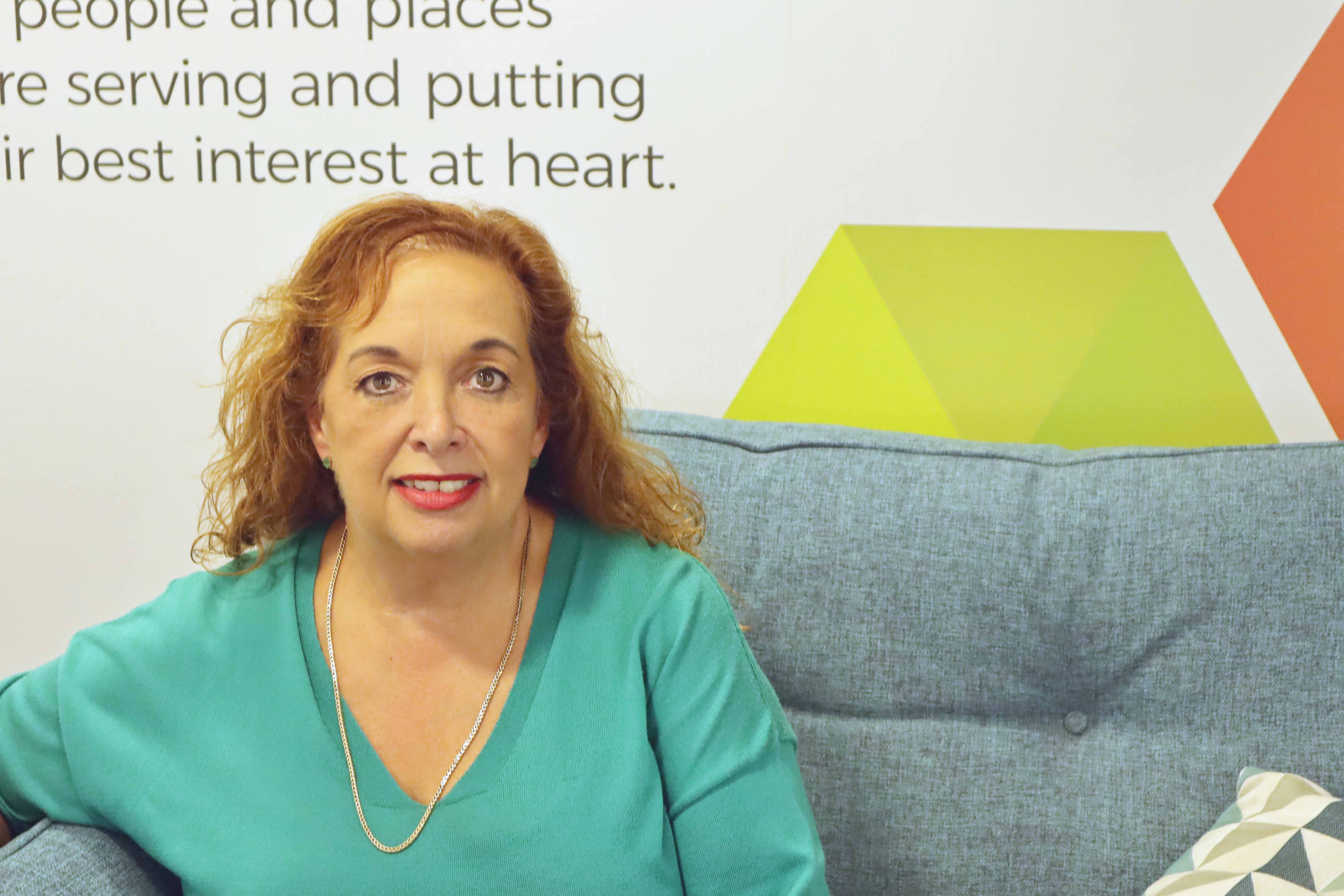 Photo of a woman sat on the sofa looking at the camera and smiling