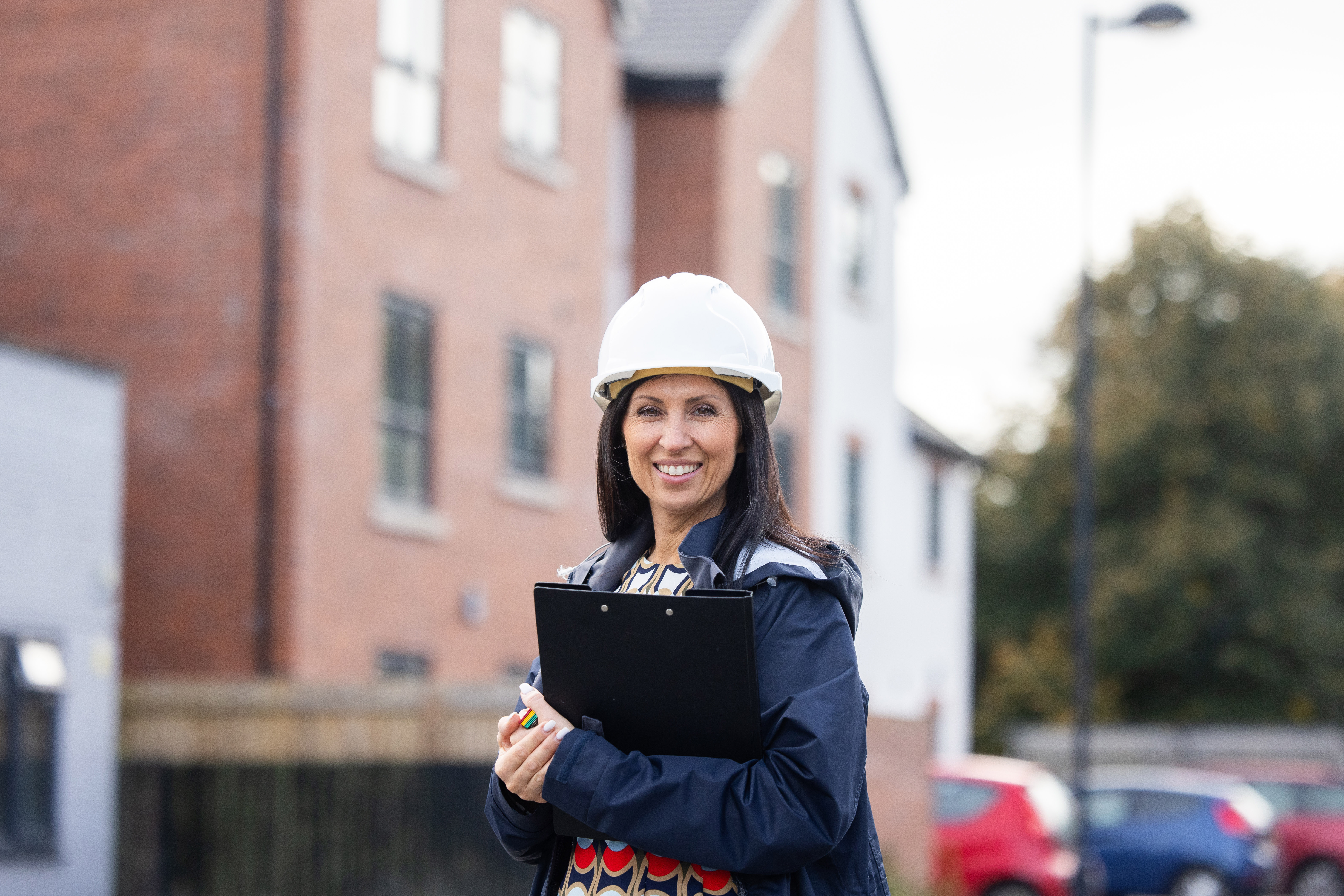 A woman standing with a clipboard smiling and looking at the camera