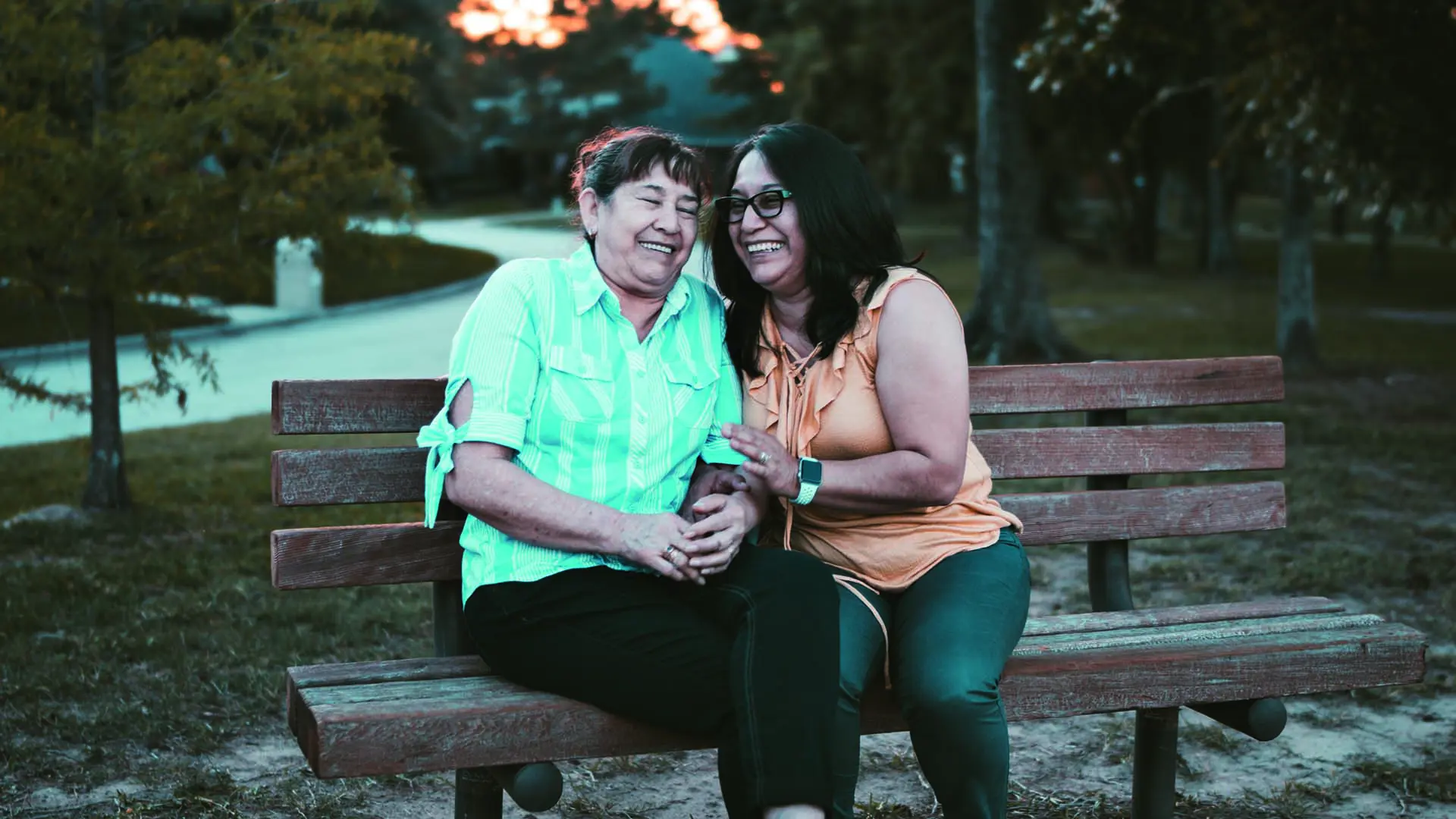 Two Women Sat On Bench Laughing