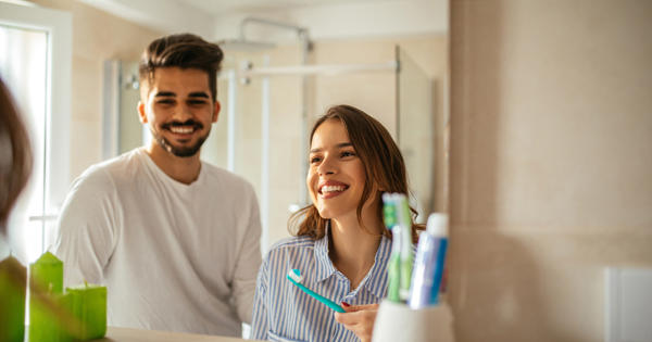 Young Couple In Bathroom Brushing Teeth