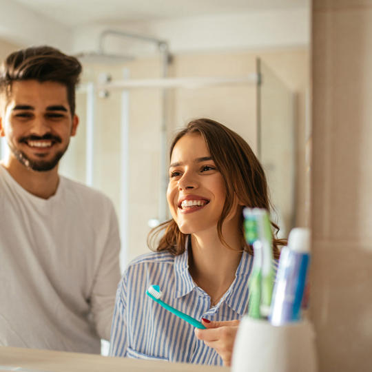 Young Couple In Bathroom Brushing Teeth