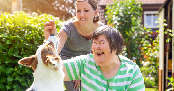 Older Mother And Daughter In Garden With Dog