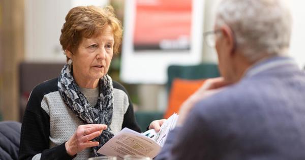 Older Woman Talking To Someone For Advice Holding Leaflet