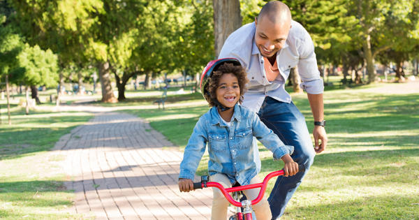 Father Teaching Young Son How To Ride A Bike